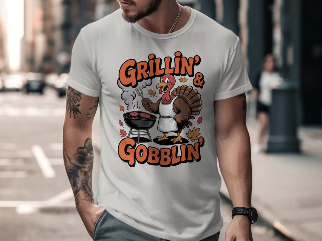 Thanksgiving men’s T-shirt with cartoon turkey grilling and “Grillin’ & Gobblin’” fall design