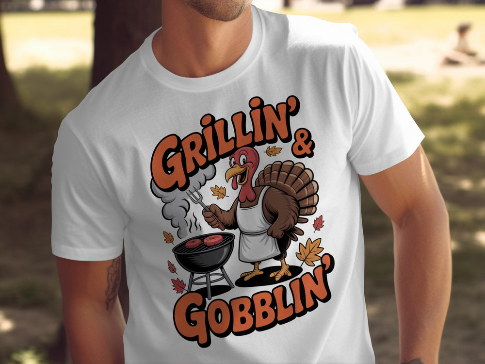 Thanksgiving men’s T-shirt with cartoon turkey grilling and “Grillin’ & Gobblin’” fall design