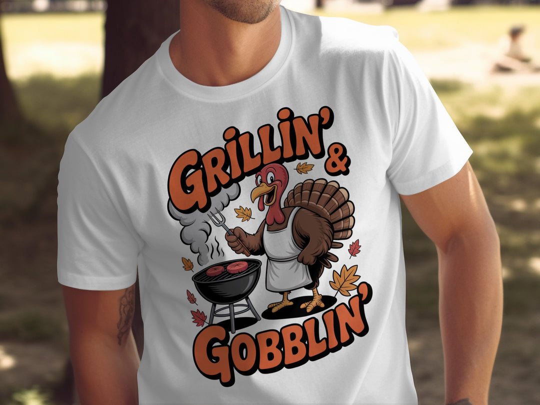 Thanksgiving men’s T-shirt with cartoon turkey grilling and “Grillin’ & Gobblin’” fall design