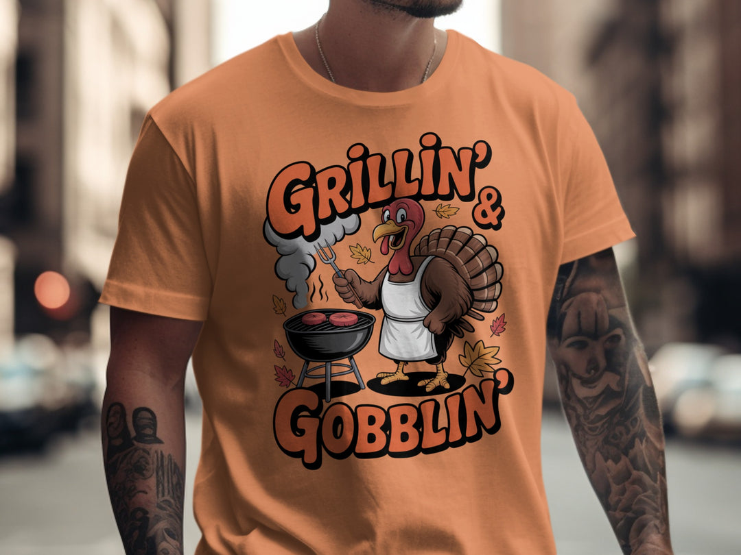 Thanksgiving men’s T-shirt with cartoon turkey grilling and “Grillin’ & Gobblin’” fall design