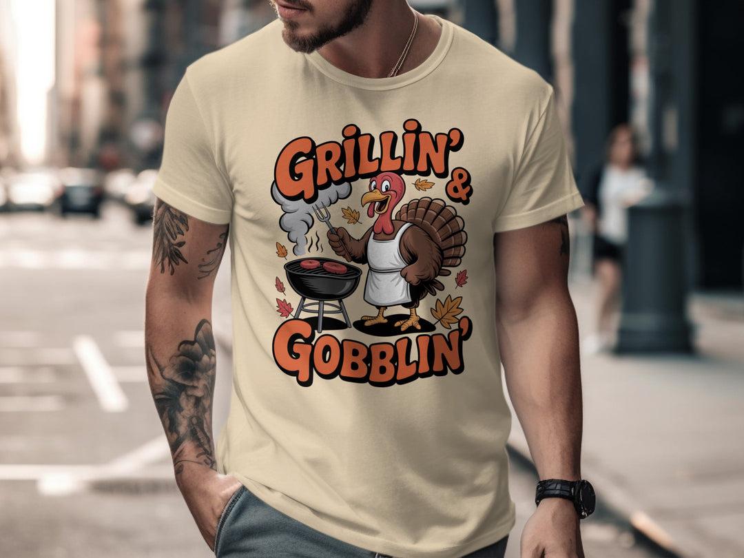 Thanksgiving men’s T-shirt with cartoon turkey grilling and “Grillin’ & Gobblin’” fall design