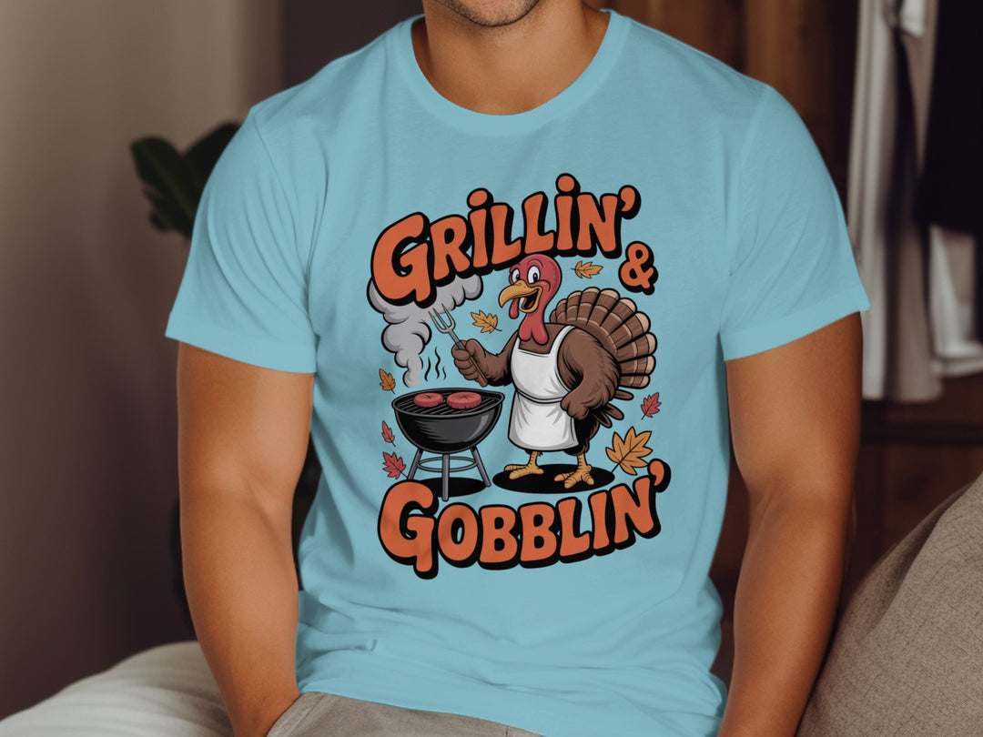 Thanksgiving men’s T-shirt with cartoon turkey grilling and “Grillin’ & Gobblin’” fall design