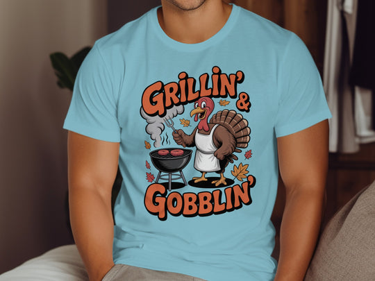 Thanksgiving men’s T-shirt with cartoon turkey grilling and “Grillin’ & Gobblin’” fall design