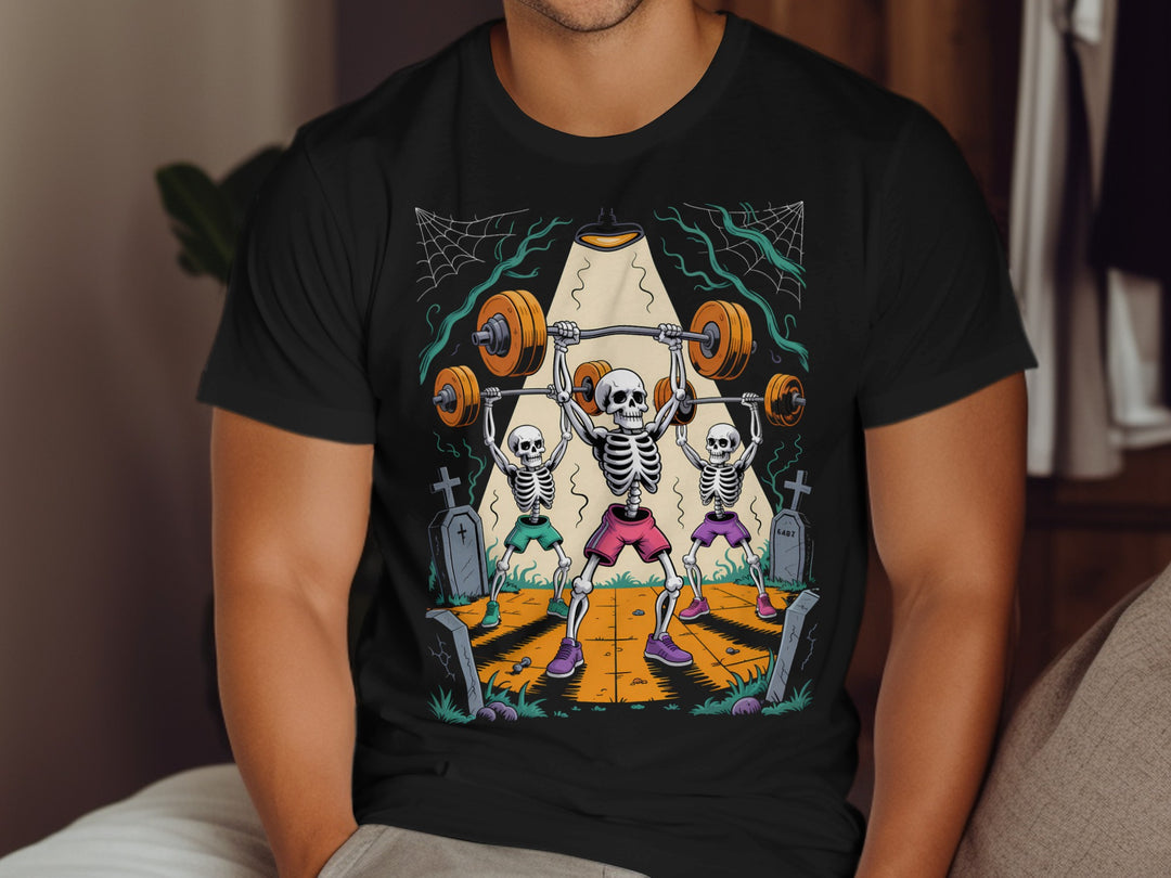 Halloween T-shirt for men with skeletons lifting barbells in a graveyard graphic