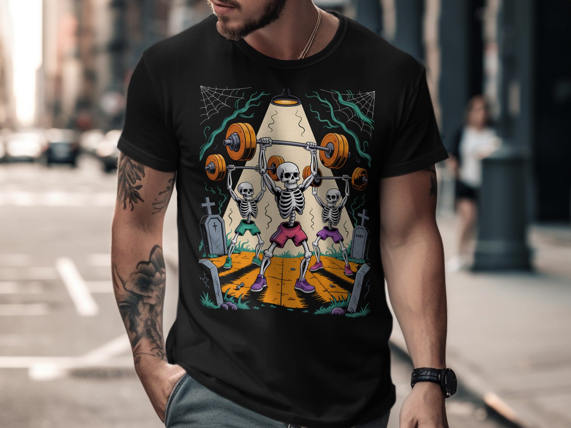Halloween T-shirt for men with skeletons lifting barbells in a graveyard graphic