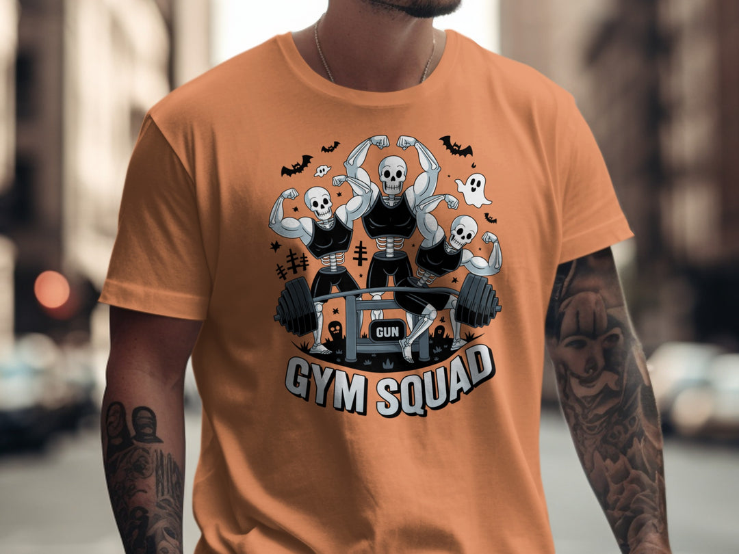 Halloween T-shirt for men with skeletons flexing around a heavy barbell, “Gym Squad” text