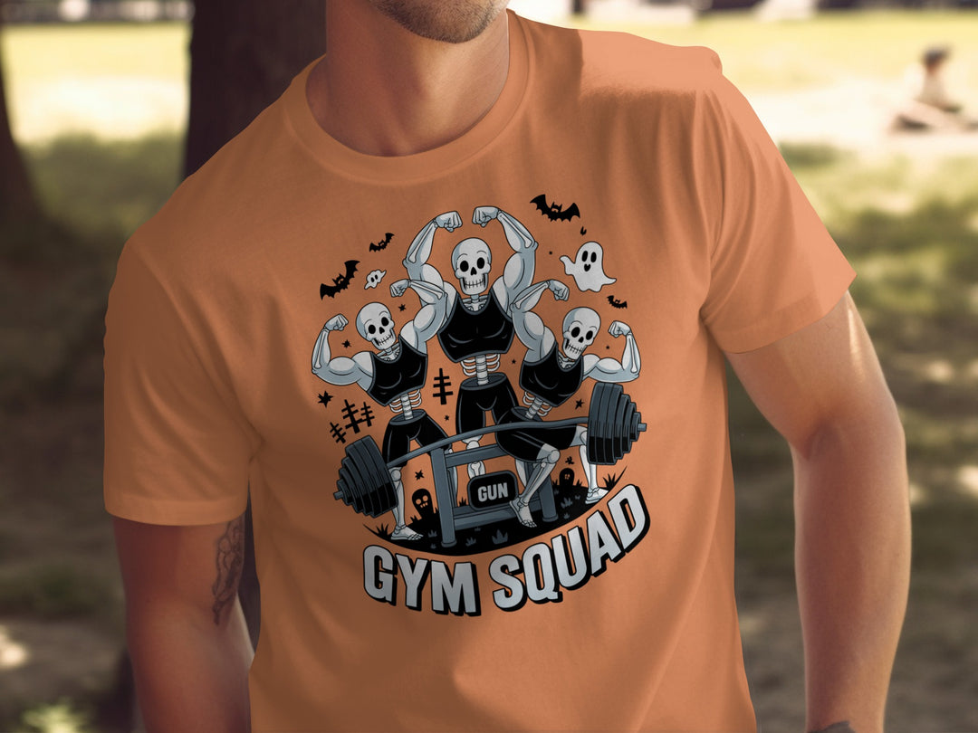 Halloween T-shirt for men with skeletons flexing around a heavy barbell, “Gym Squad” text