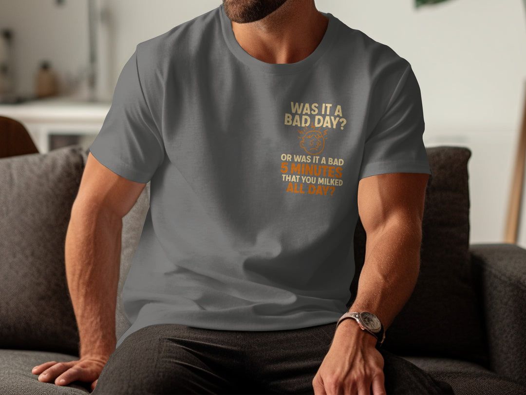 Person wearing a charcoal t-shirt with a humorous print, sitting on a couch.