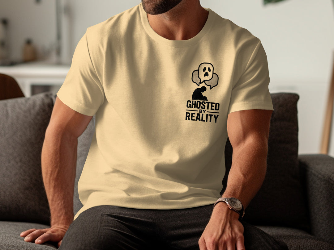 Person wearing a beige t-shirt with a graphic design and text, sitting on a couch.