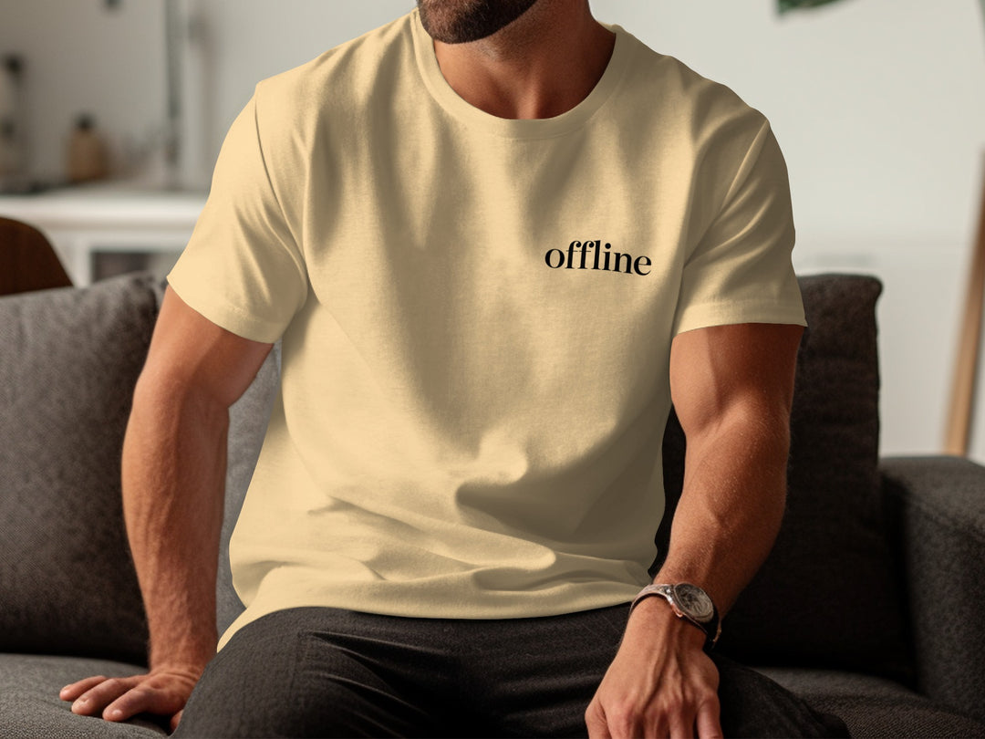 Person wearing a beige t-shirt with 'offline' text, sitting on a couch.