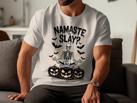 Person wearing a natural color t-shirt with Halloween-themed design featuring a skeleton and pumpkins.