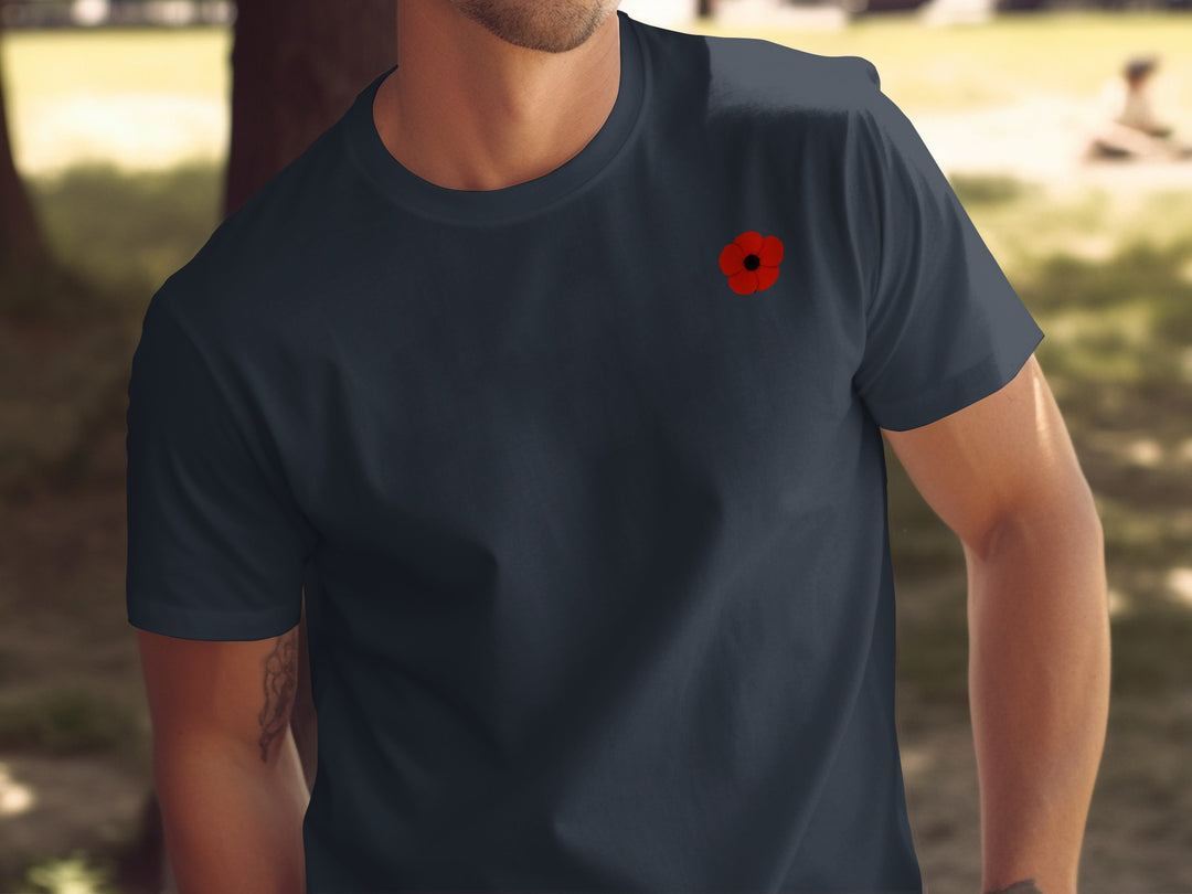 Person wearing a navy blue t-shirt with a red poppy design outdoors.