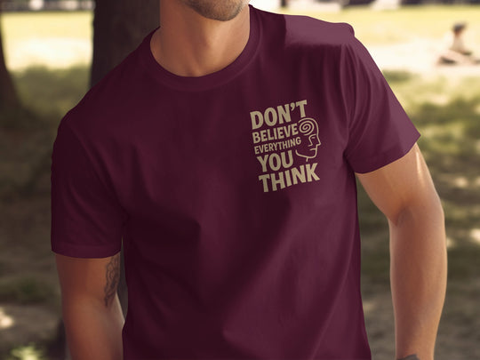 Person wearing a maroon t-shirt with a motivational quote outdoors