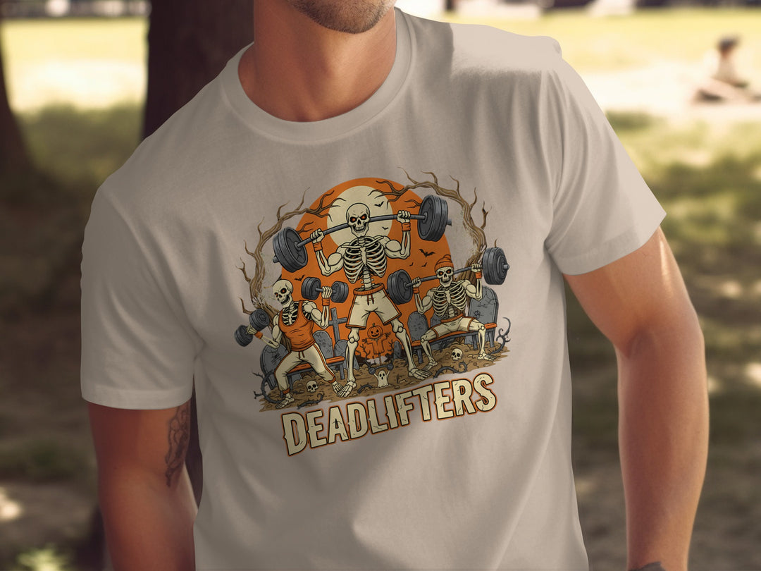 Person wearing a beige t-shirt with a graphic design of skeletons lifting weights and the text 'DEADLIFTERS'.