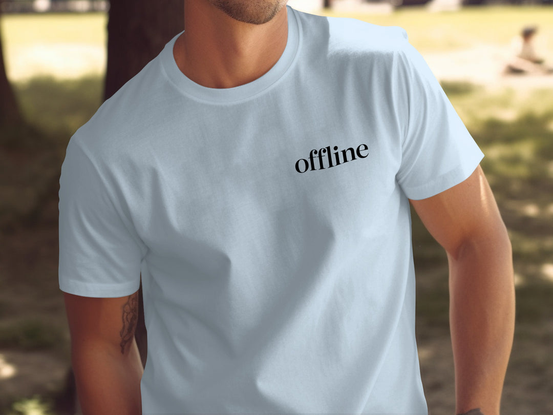 Person wearing a light blue t-shirt with 'offline' text in a park setting