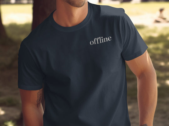 Person wearing a navy blue t-shirt with 'offline' text in an outdoor setting