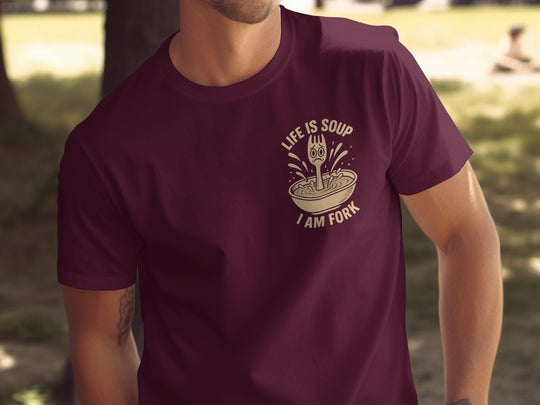Person wearing a maroon t-shirt with a graphic design and text.