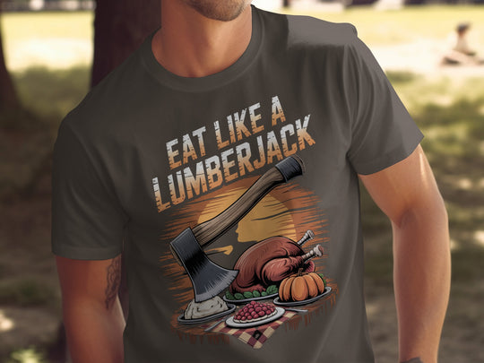 Person wearing a dark chocolate t-shirt with 'Eat Like a Lumberjack' graphic design outdoors.