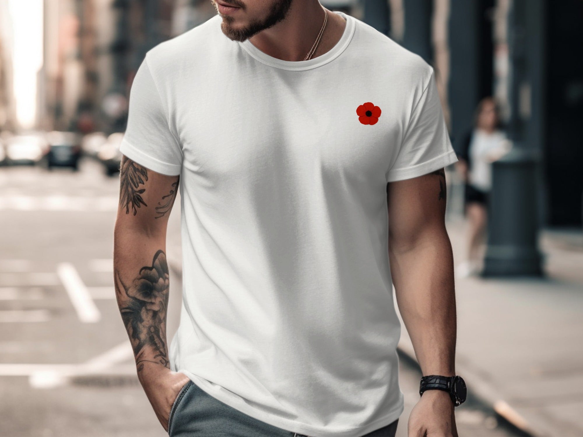 Man wearing a white t-shirt with a red poppy design on a city street.