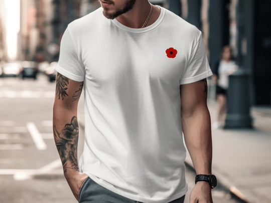 Man wearing a white t-shirt with a red poppy design on a city street.