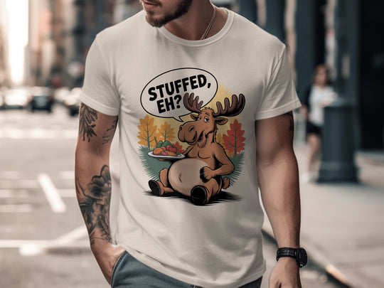 Person wearing a natural color t-shirt with a cartoon moose graphic and text on a city street.