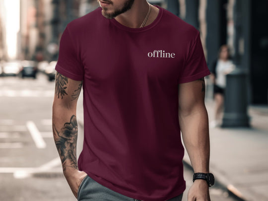Man wearing a maroon t-shirt with 'offline' text on a city street.