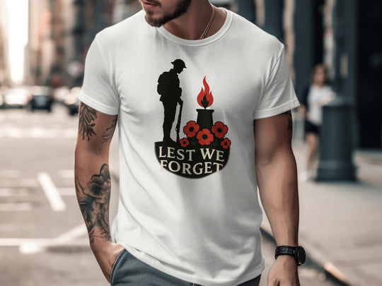 Man wearing a white t-shirt with a memorial design and 'Lest We Forget' text on a city street.