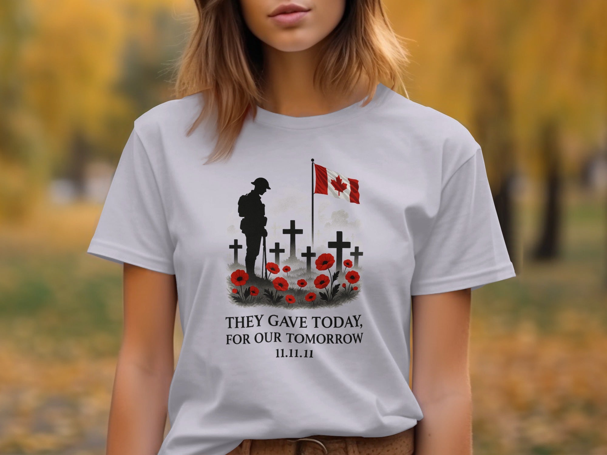 Person wearing a lavender t-shirt with a graphic design featuring crosses, poppies, and a flag, set against a blurred outdoor background.