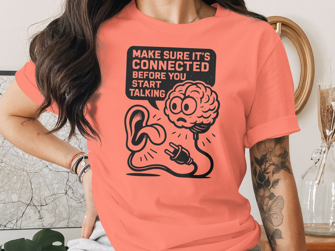 Person wearing a coral t-shirt with a graphic design and text.