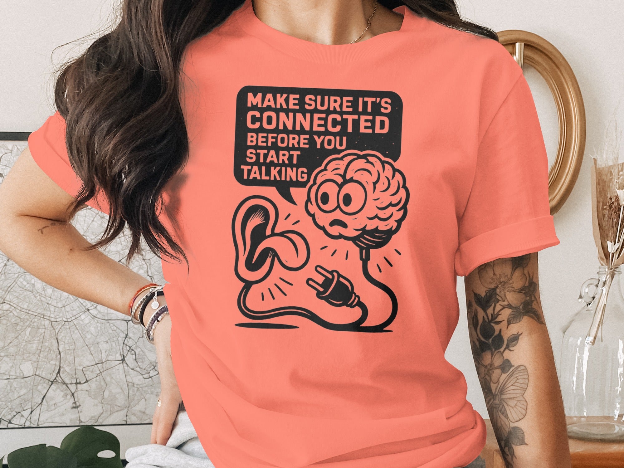 Person wearing a coral t-shirt with a graphic design and text.