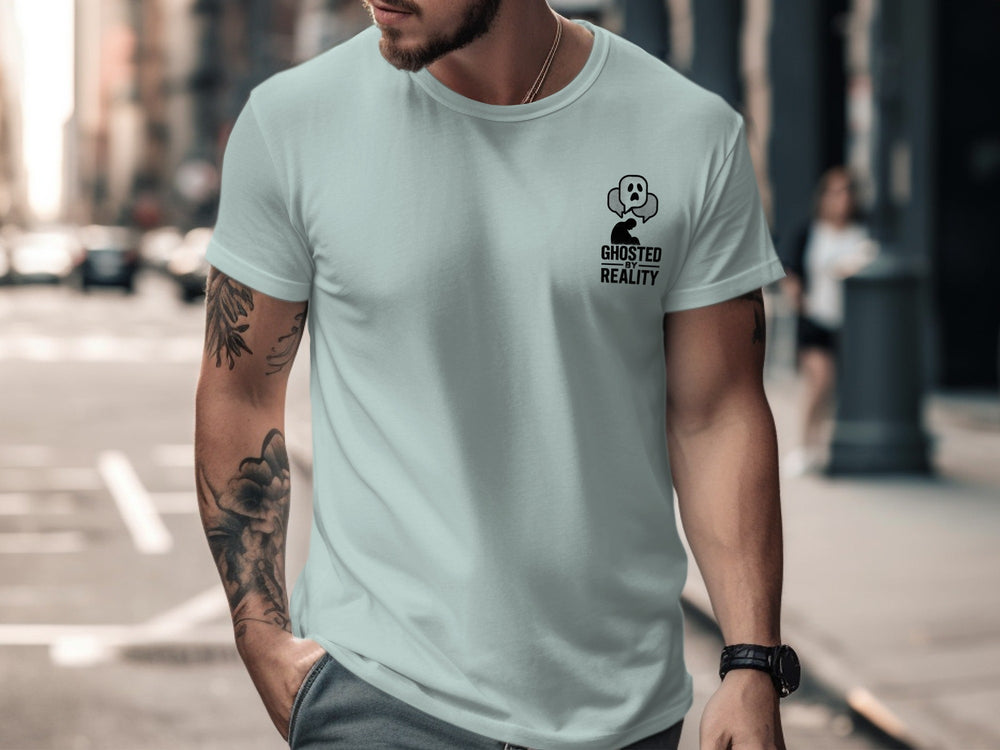 Man wearing a light blue t-shirt with a graphic design on a city street.