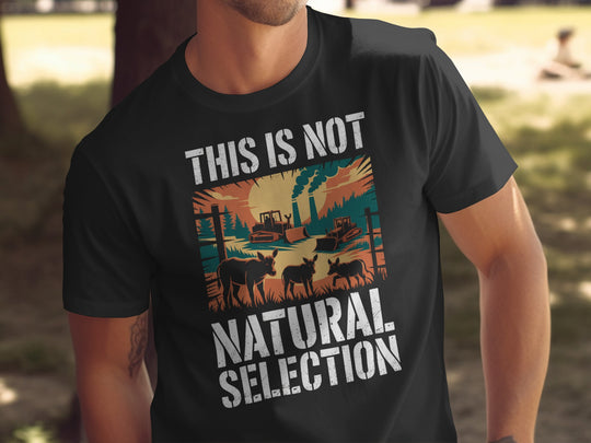 Person wearing a black t-shirt with a graphic and text 'THIS IS NOT NATURAL SELECTION' outdoors.