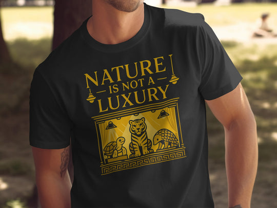 Black t-shirt with yellow graphic and text 'Nature is not a luxury' worn by a person outdoors.