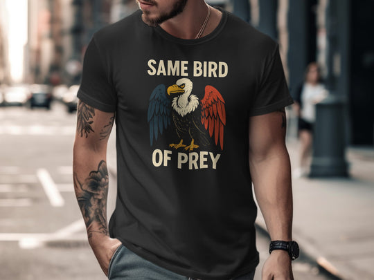Man wearing a black t-shirt with an eagle graphic and text on a city street.