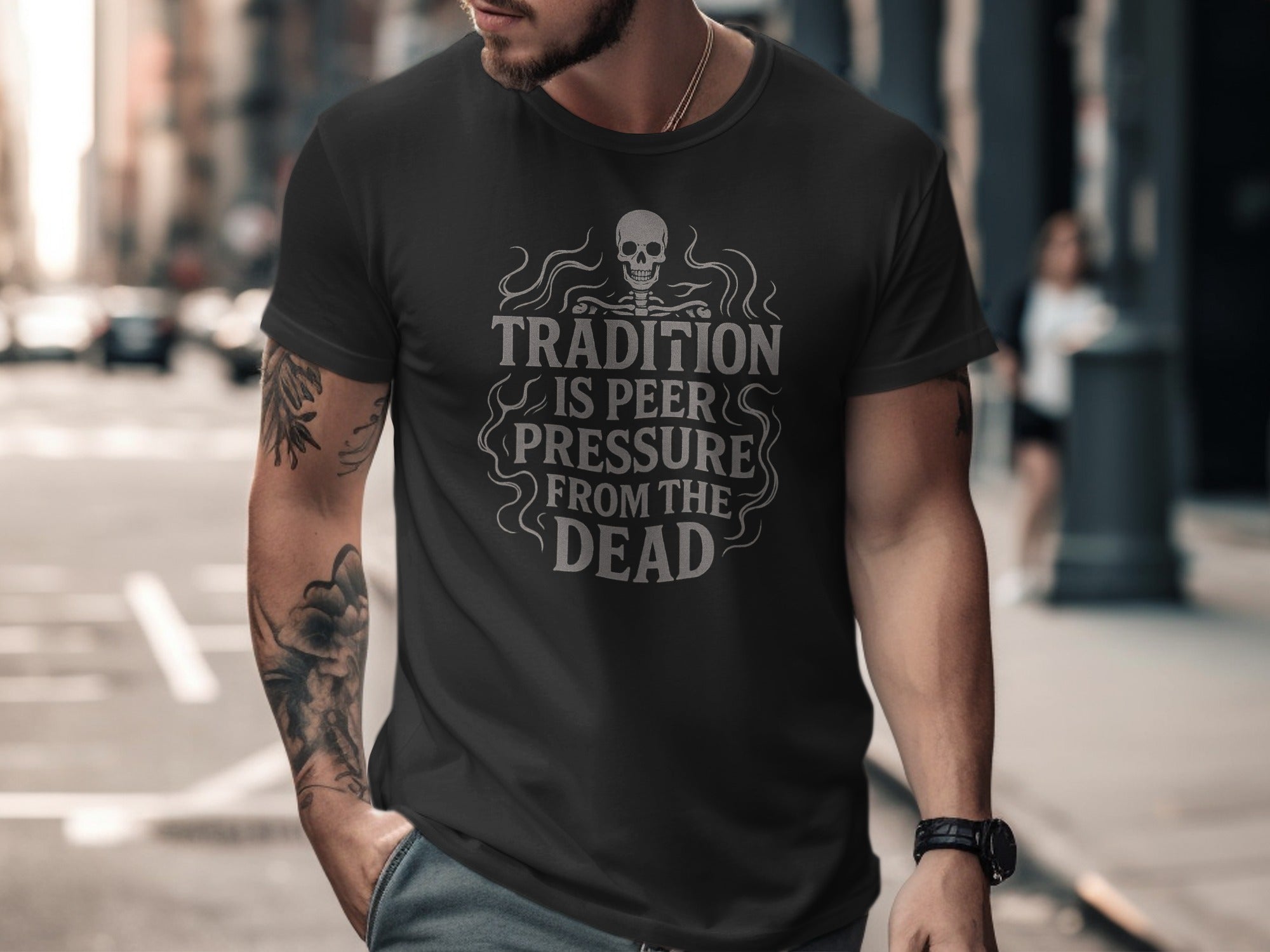Man wearing a black t-shirt with a skull design and text on a city street.