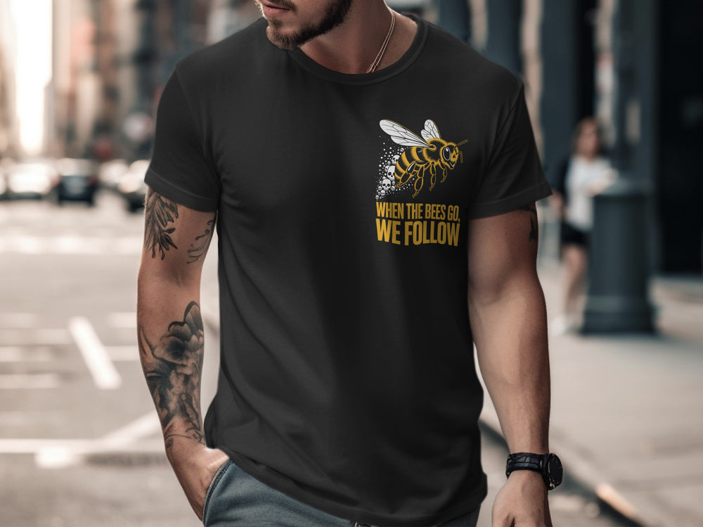 Man wearing a black t-shirt with a bee graphic and text on a city street.