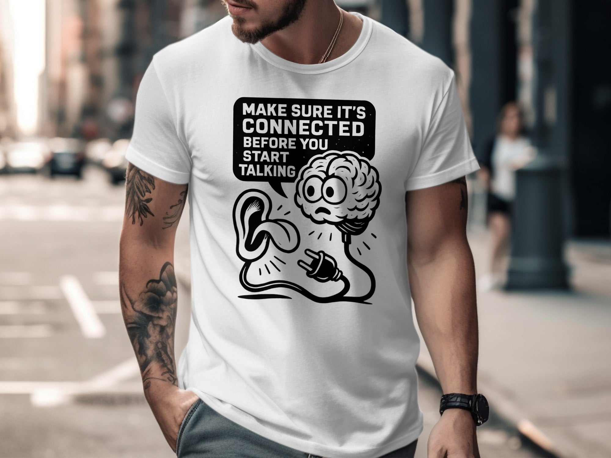 Person wearing a white t-shirt with a graphic design and text on a city street.