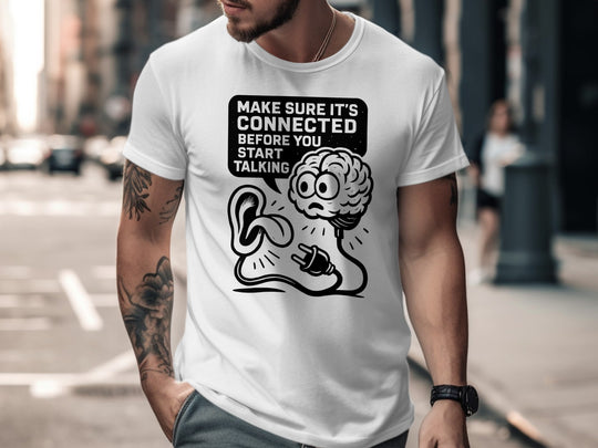 Person wearing a white t-shirt with a graphic design and text on a city street.