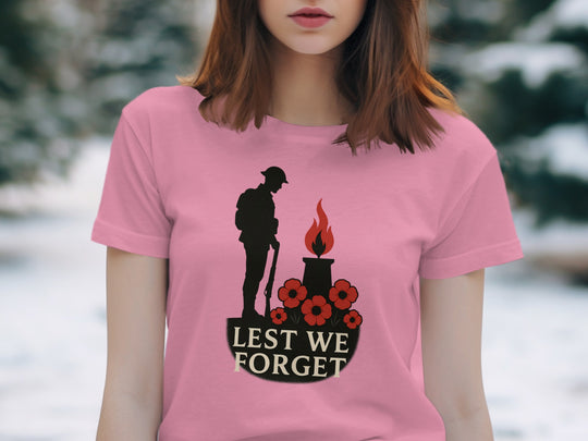 Person wearing a pink t-shirt with a 'Lest We Forget' design in a snowy outdoor setting