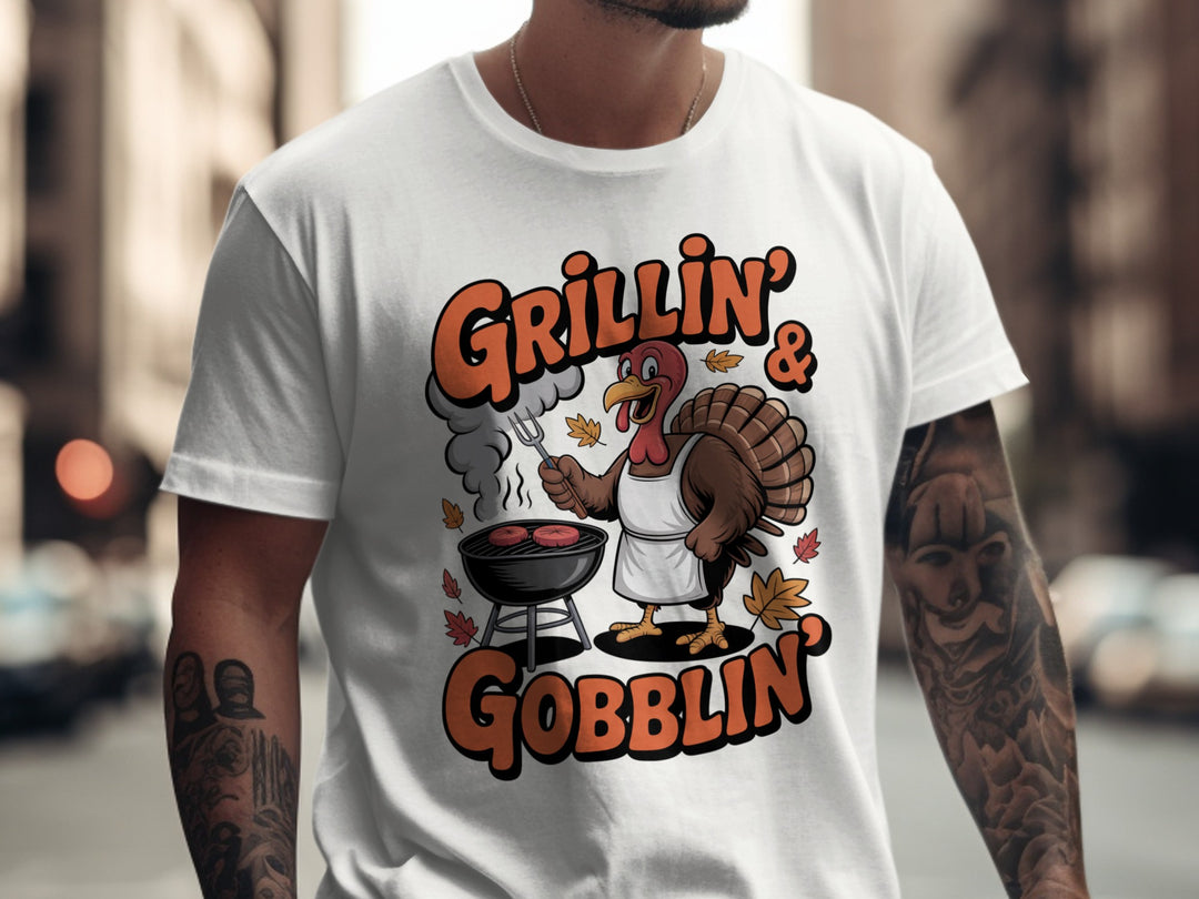 Person wearing a white t-shirt with a turkey graphic and text 'Grillin' & Gobblin' on a city street.