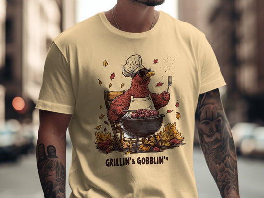 Person wearing a yellow haze t-shirt with a graphic of a rooster cooking on a grill and the text 'Grillin' & Gobblin''.