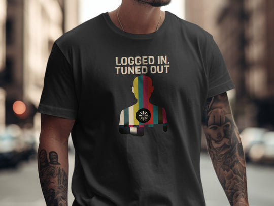 Person wearing a black t-shirt with colorful graphic and text 'LOGGED IN, TUNED OUT' on a city street.