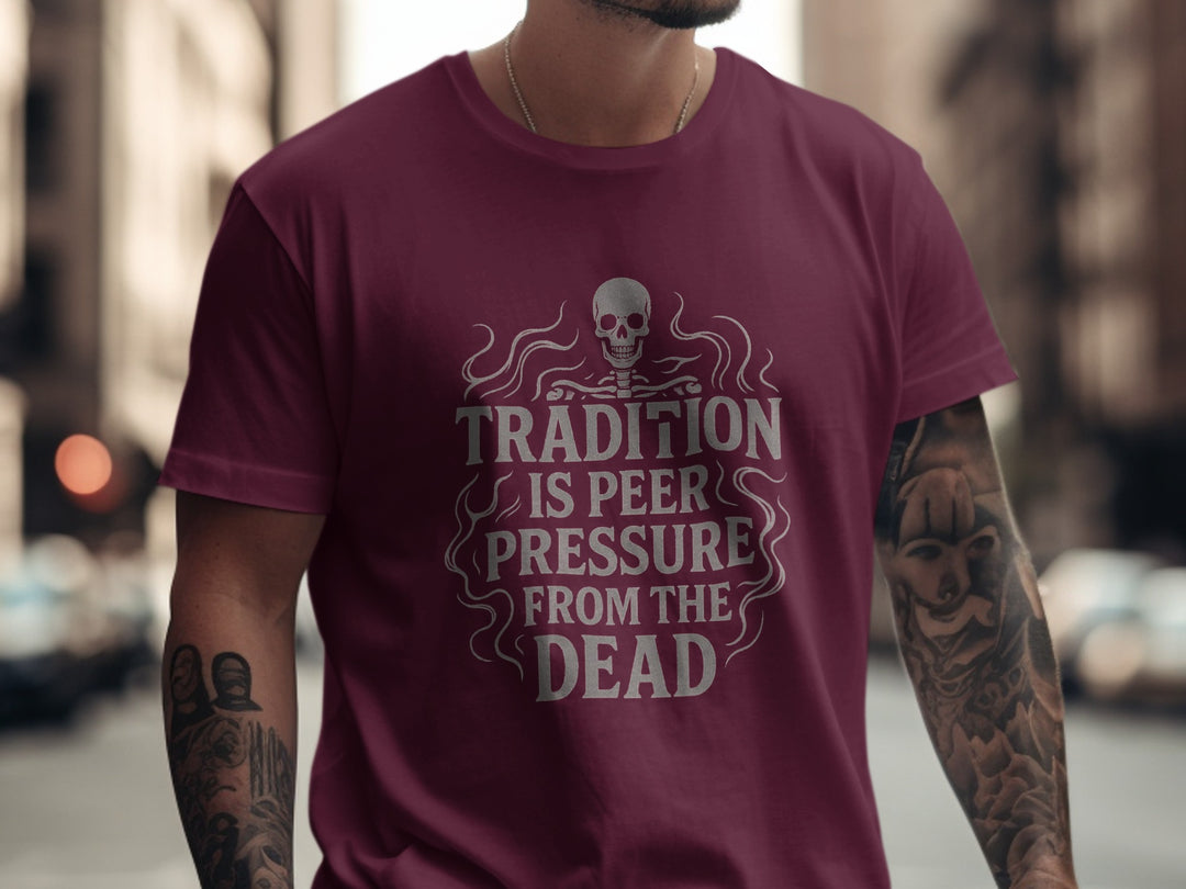Person wearing a maroon t-shirt with a skull design and text in an urban setting