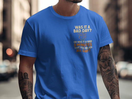 Person wearing a blue t-shirt with a humorous text design on a city street.