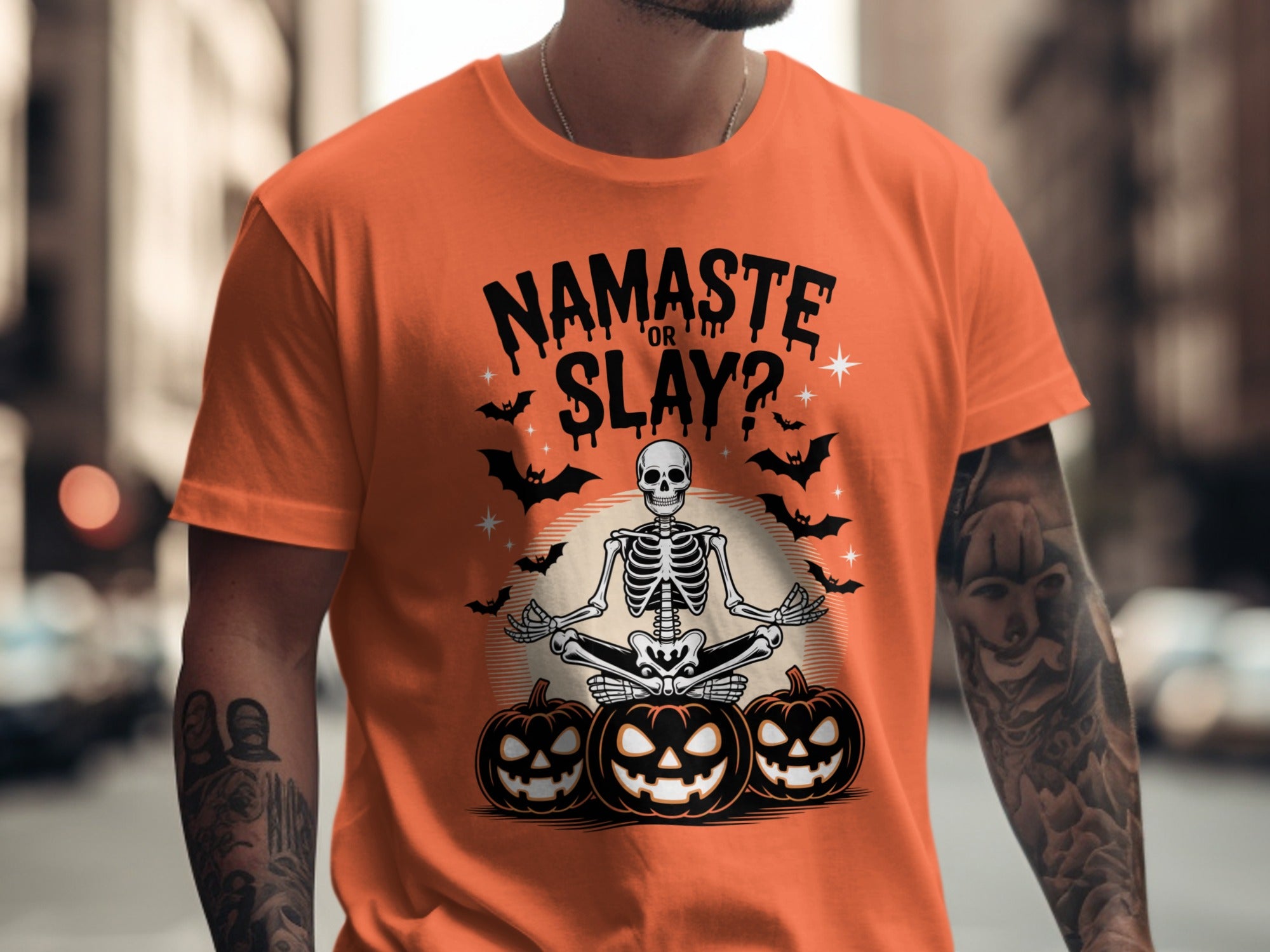 Person wearing an orange t-shirt with a Halloween-themed design featuring a skeleton and pumpkins.
