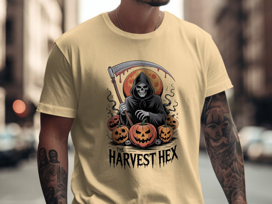 Person wearing a beige t-shirt with a graphic design of a skeleton holding a scythe and pumpkins, with 'The Harvest Hex' text.