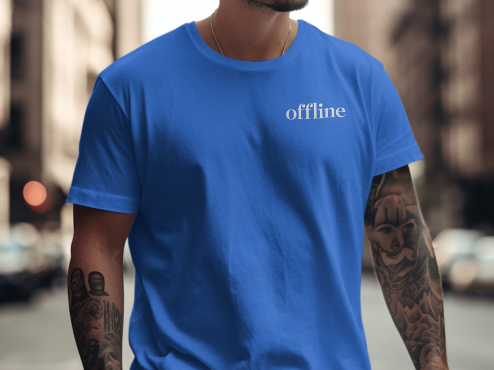 Person wearing a blue t-shirt with 'offline' text on a city street.