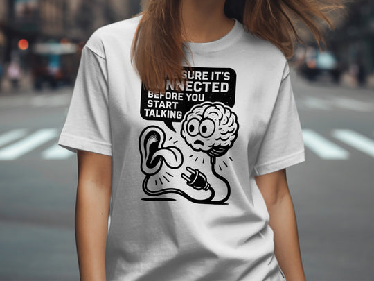 Person wearing a white t-shirt with a graphic design and text on a city street background