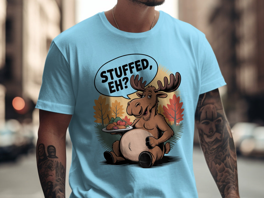Person wearing a sky blue t-shirt with a cartoon moose graphic and text 'STUFFED, EH?' in an urban setting.