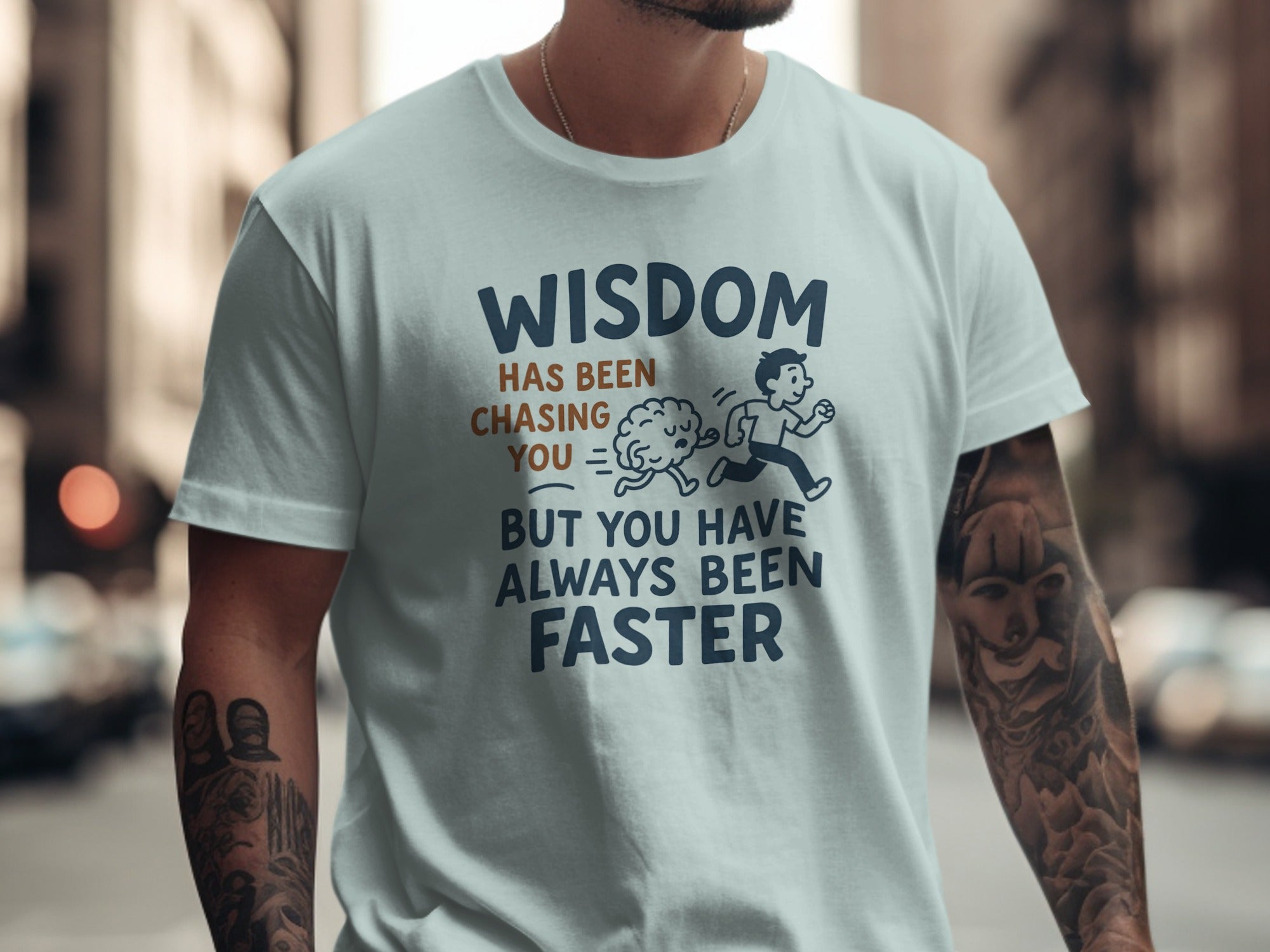 Person wearing a light blue t-shirt with a humour comment and graphic on a city street background.